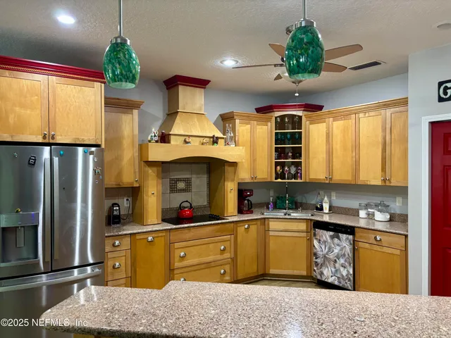 a kitchen with stainless steel appliances granite countertop a sink dishwasher a refrigerator cabinets and wooden floor