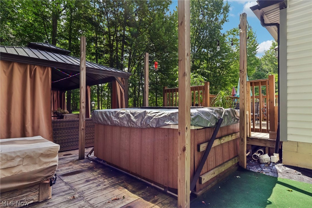 3213 Bates Road Madison, OH 44057 - Photo 35 of 45 Expansive multi-level wood deck featuring a covered outdoor structure with privacy curtains and a built-in spa with a protective cover