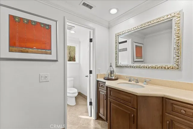 a view of a white house with a yard plants and large tree