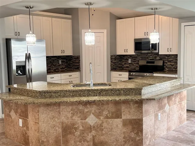 a kitchen with stainless steel appliances granite countertop a sink a stove and a refrigerator