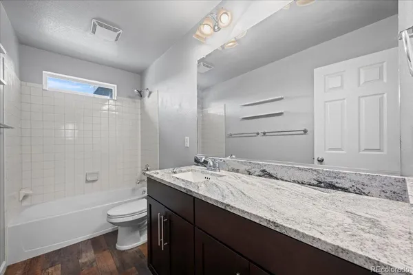 a bathroom with a granite countertop sink a toilet a mirror and bathtub