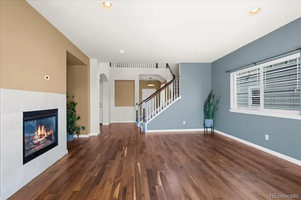 a view of an empty room with wooden floor fireplace and a window