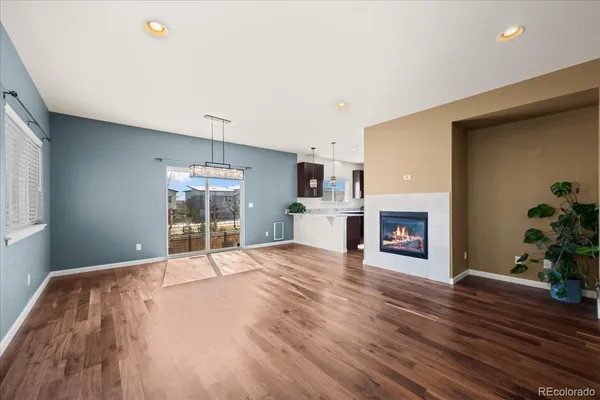 a view of an empty room with wooden floor and a fireplace