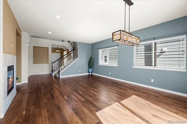 a view of an empty room with wooden floor kitchen view and a window