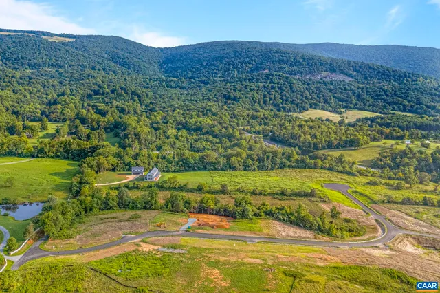 a front view of a house with a garden and lake view