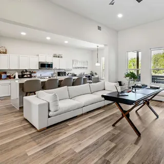 a living room with furniture a rug kitchen view and a wooden floor