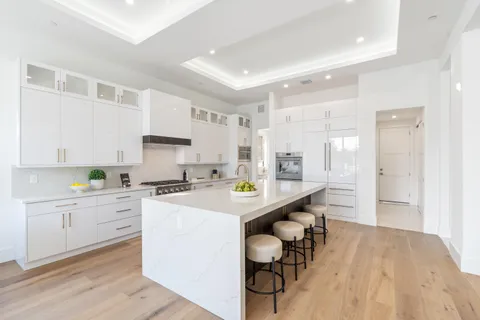 a kitchen with granite countertop a dining table chairs cabinets and stainless steel appliances