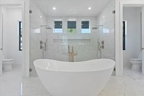 a spacious bathroom with a bathtub shower sink mirror and toilet