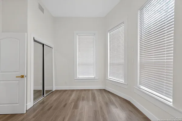 an empty room with wooden floor and windows