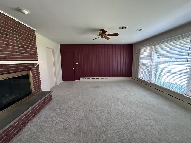 a view of an empty room with a fireplace and a window