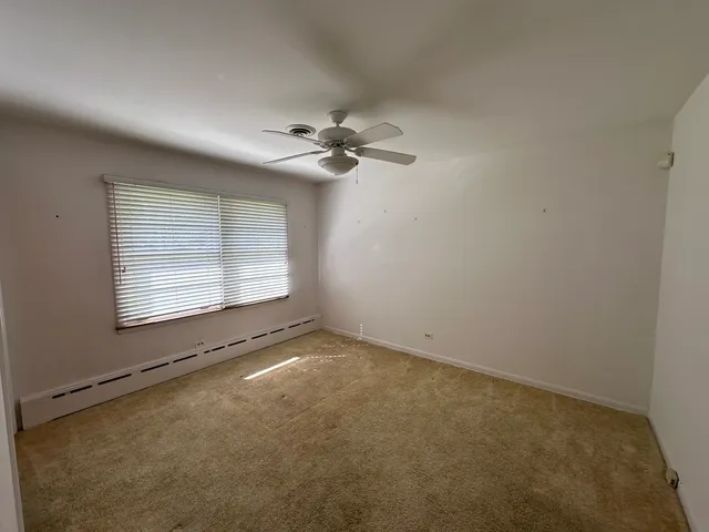 an empty room with a chandelier fan and windows
