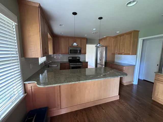 a kitchen with kitchen island granite countertop a sink a counter space appliances and cabinets