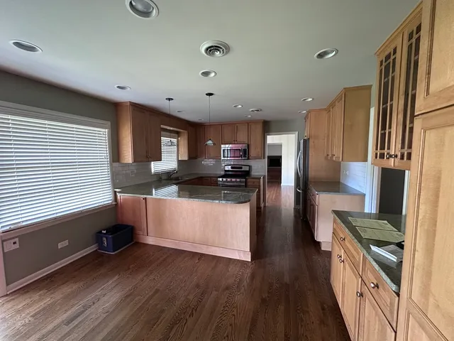 a kitchen with stainless steel appliances granite countertop a refrigerator a stove top oven a sink dishwasher and wooden floor