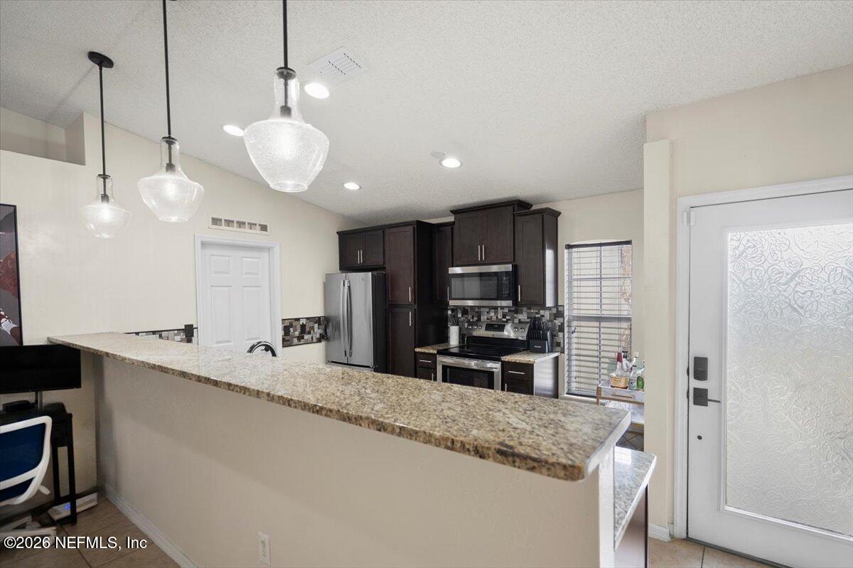 10310 Woodley Point Road Jacksonville, FL 32218 - Photo 3 of 30 a kitchen with stainless steel appliances granite countertop a sink a stove and a refrigerator