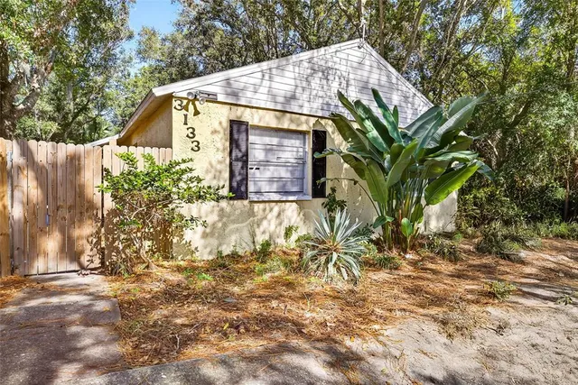 a view of a backyard with large trees and a barn