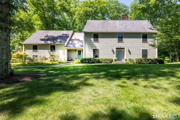 a front view of a house with a garden and trees