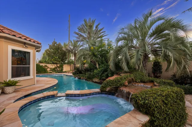 a view of a swimming pool with a lounge chair and palm trees