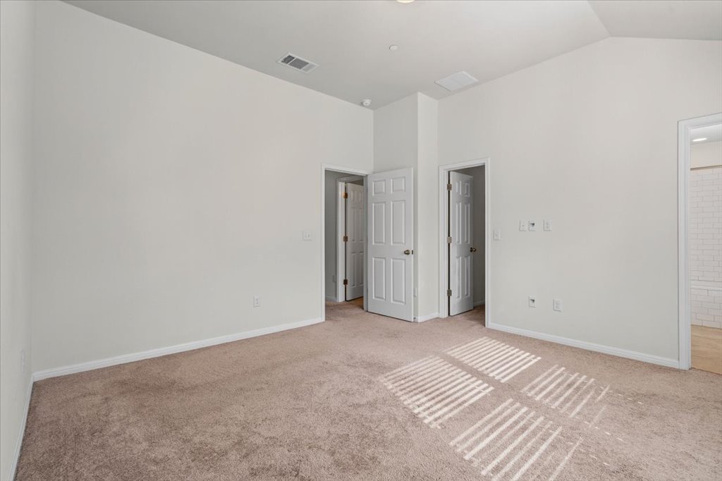 1609 Catalan Road, Unit 1802 Austin, TX 78748 - Photo 17 of 25 Unfurnished bedroom featuring light colored carpet, ensuite bath, and high vaulted ceiling