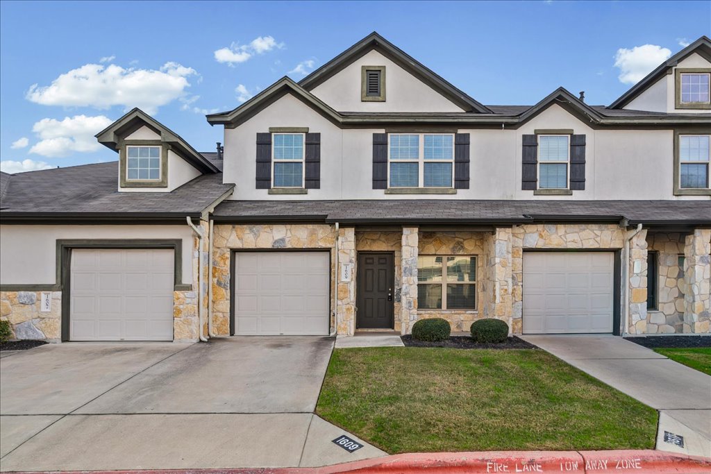 1609 Catalan Road, Unit 1802 Austin, TX 78748 - Photo 2 of 25 View of front of house with stone siding, concrete driveway, stucco siding, a front lawn, and a garage