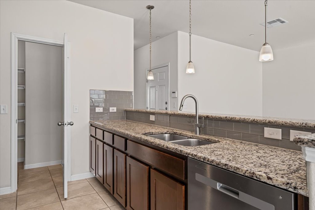 1609 Catalan Road, Unit 1802 Austin, TX 78748 - Photo 8 of 25 Kitchen with stainless steel dishwasher, light stone countertops, hanging light fixtures, dark brown cabinets, and tasteful backsplash