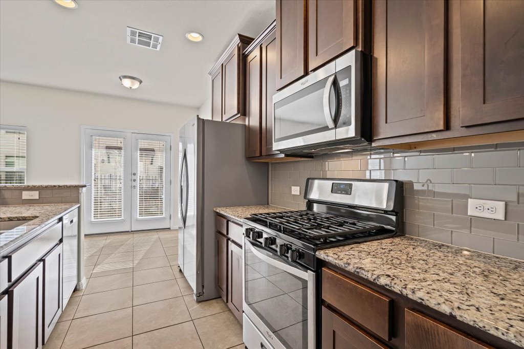 1609 Catalan Road, Unit 1802 Austin, TX 78748 - Photo 9 of 25 Kitchen featuring appliances with stainless steel finishes, light stone counters, dark brown cabinets, light tile patterned floors, and recessed lighting