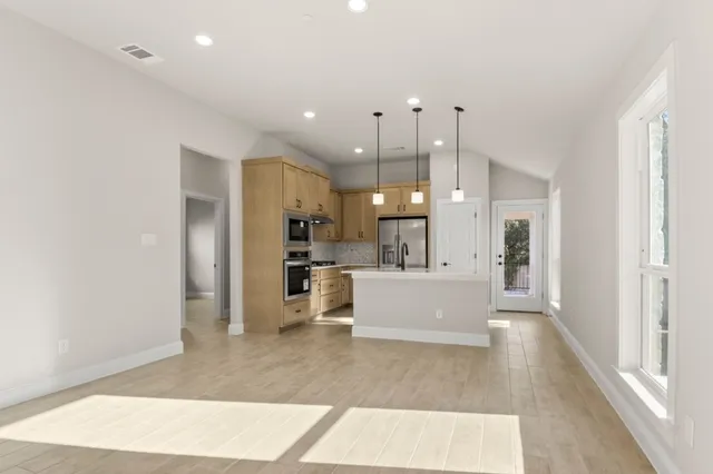 a view of a kitchen with kitchen island a refrigerator a sink dishwasher with a dining table and chairs