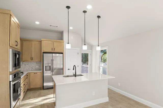 a view of kitchen island with stainless steel appliances sink and refrigerator