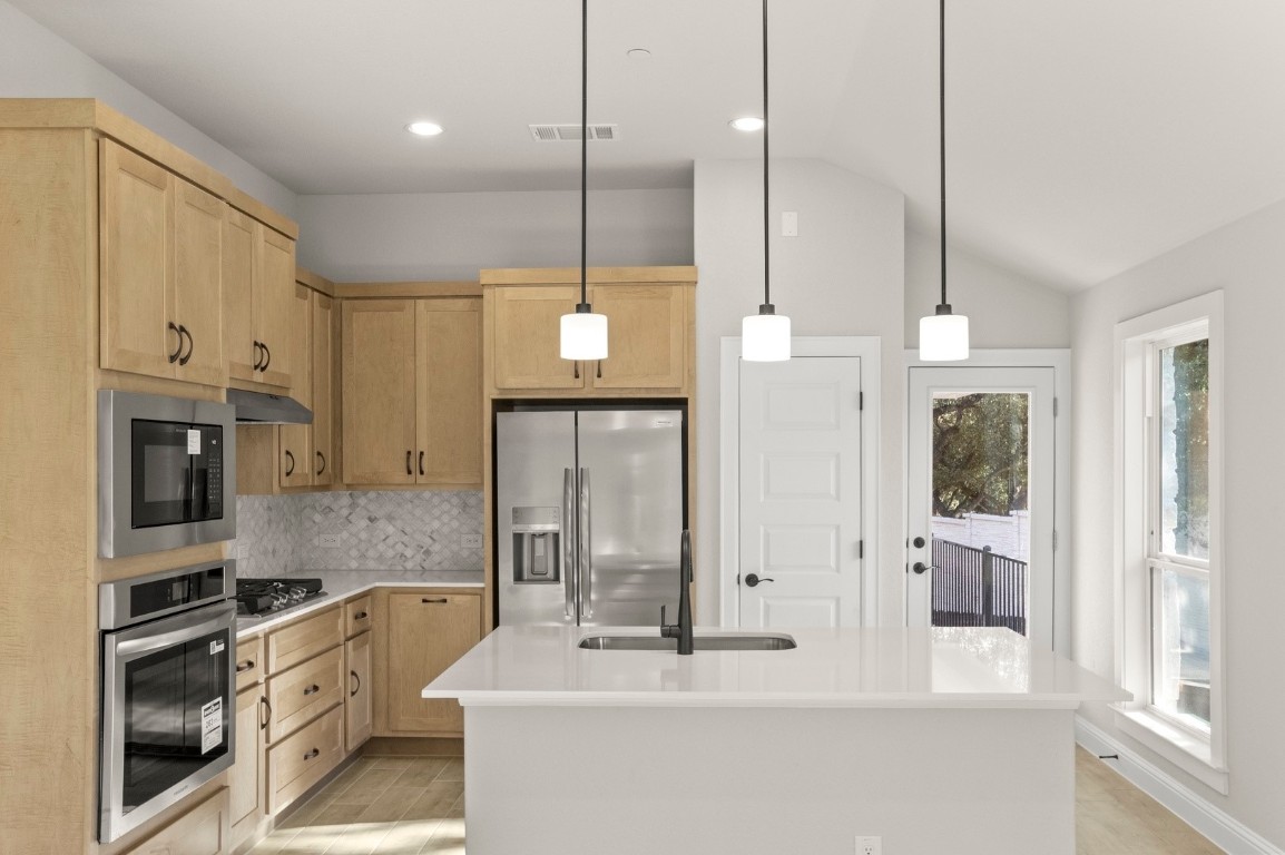 2605 Sam Bass Road, Unit 65 Round Rock, TX 78681 - Photo 19 of 33 a kitchen with stainless steel appliances kitchen island granite countertop a refrigerator a sink and a fireplace