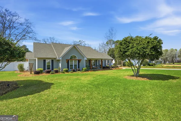 a front view of a house with garden and trees