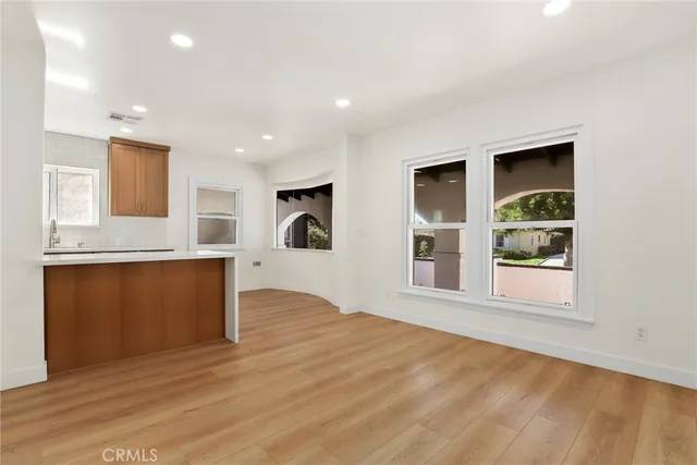 a view of an empty room with a window and kitchen