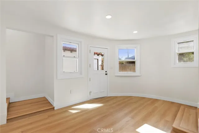 a view of empty room with wooden floor and window