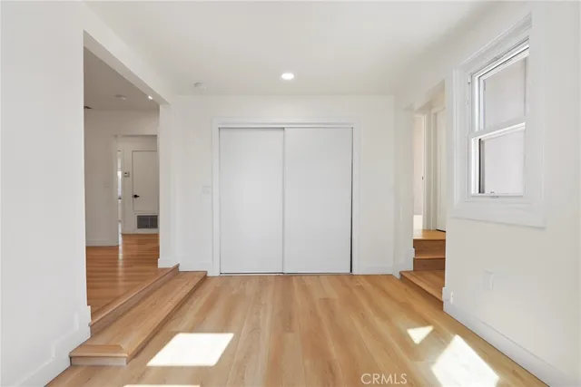 a view of hallway with wooden floor and cabinet