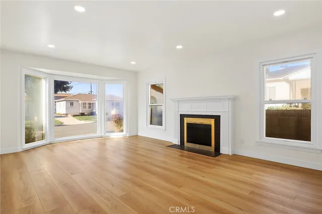 a view of an empty room with a fireplace and wooden floor