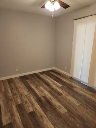 a view of a room with wooden floor and a ceiling fan