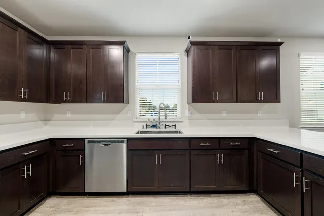 a large kitchen with stainless steel appliances granite countertop a sink dishwasher stove and wooden cabinets