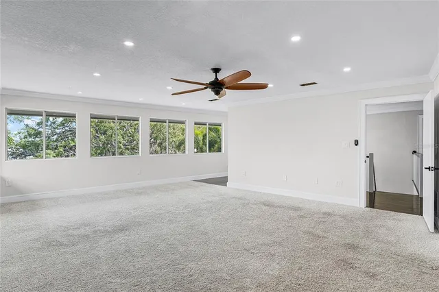 an empty room with wooden floor cabinet and windows