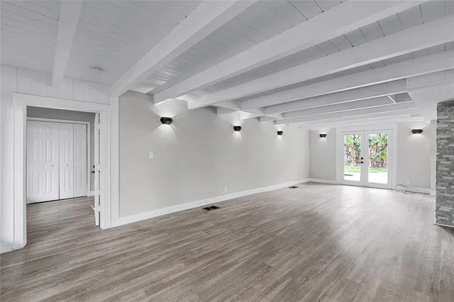 a view of an empty room with wooden floor fireplace and a window