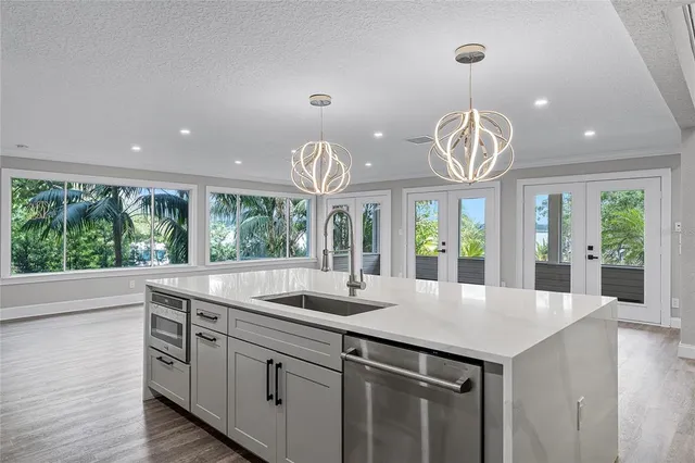 a view of a kitchen counter space with a sink and dishwasher with wooden floor