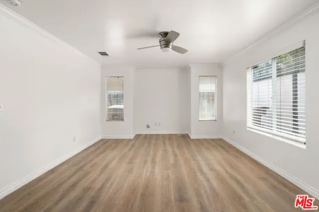 a view of an empty room with a window and wooden floor