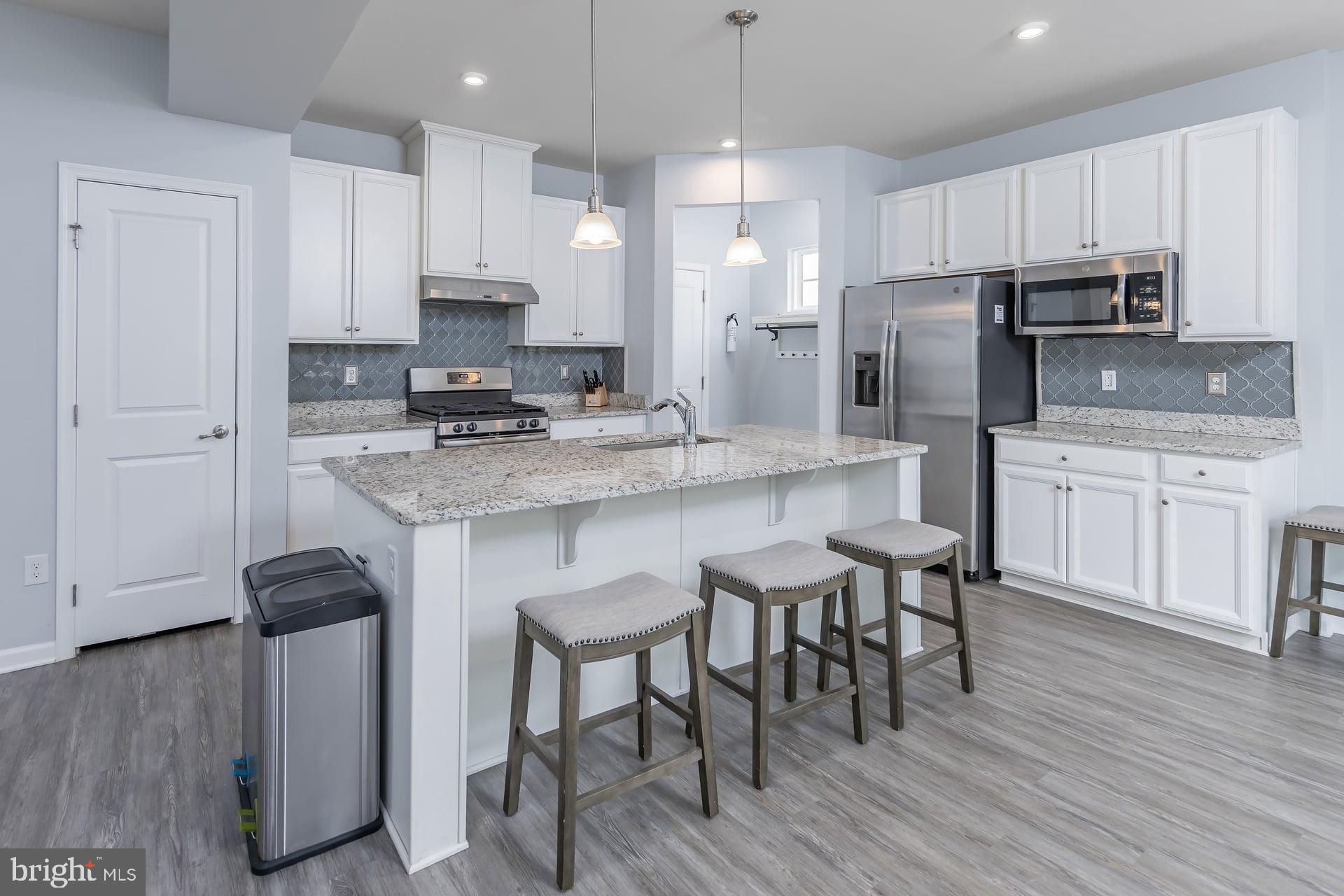 53 Oak Ln. Carneys Point, NJ 08069 - Photo 7 of 28 a kitchen with stainless steel appliances a stove a sink a microwave a refrigerator and white cabinets with wooden floor