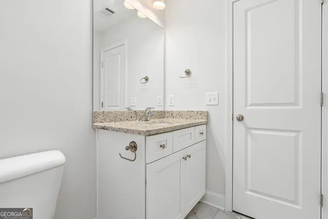 a bathroom with a granite countertop sink and a toilet