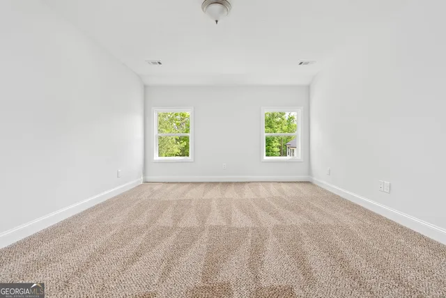 a view of an empty room with window and wooden floor