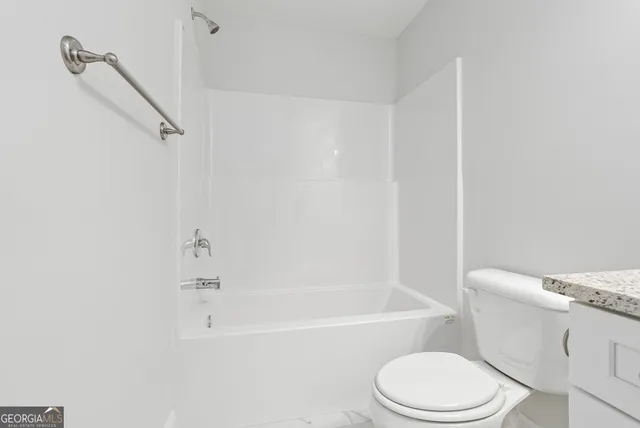 a white toilet and tub sitting next to a bathroom sink