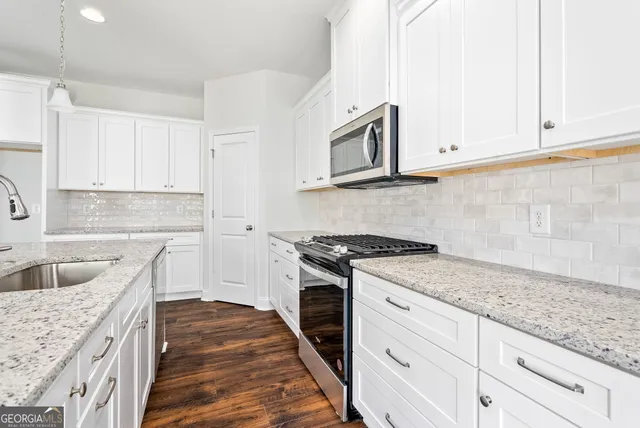 a kitchen with granite countertop a sink dishwasher stove and cabinets