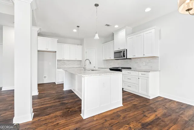 a kitchen with kitchen island granite countertop a sink cabinets and stainless steel appliances