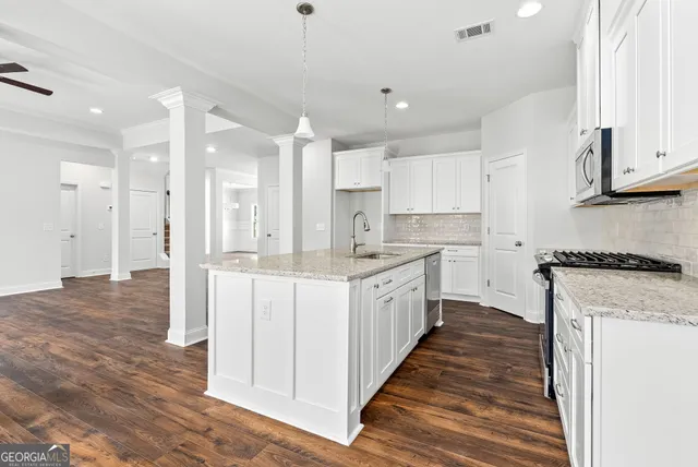 a large kitchen with stainless steel appliances kitchen island granite countertop a stove a sink and white cabinets
