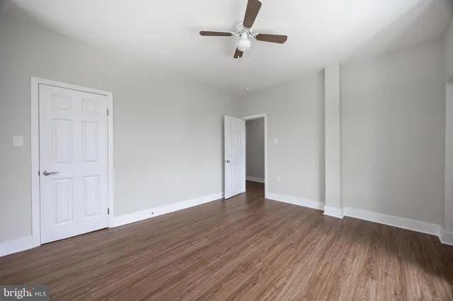 an empty room with wooden floor fan and windows