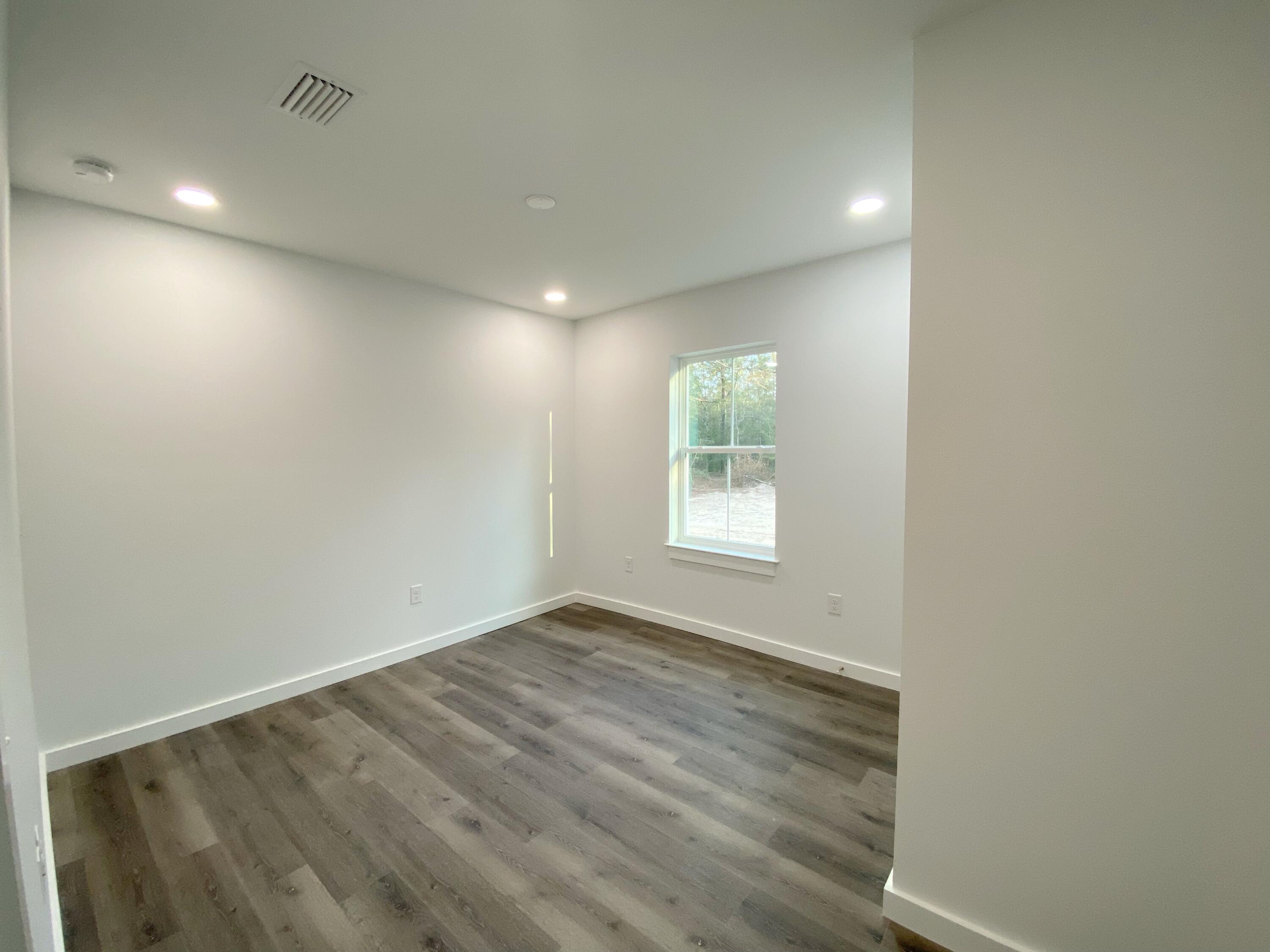 211 West Renoir Road DeFuniak Springs, FL 32433 - Photo 11 of 19 an empty room with wooden floor and windows