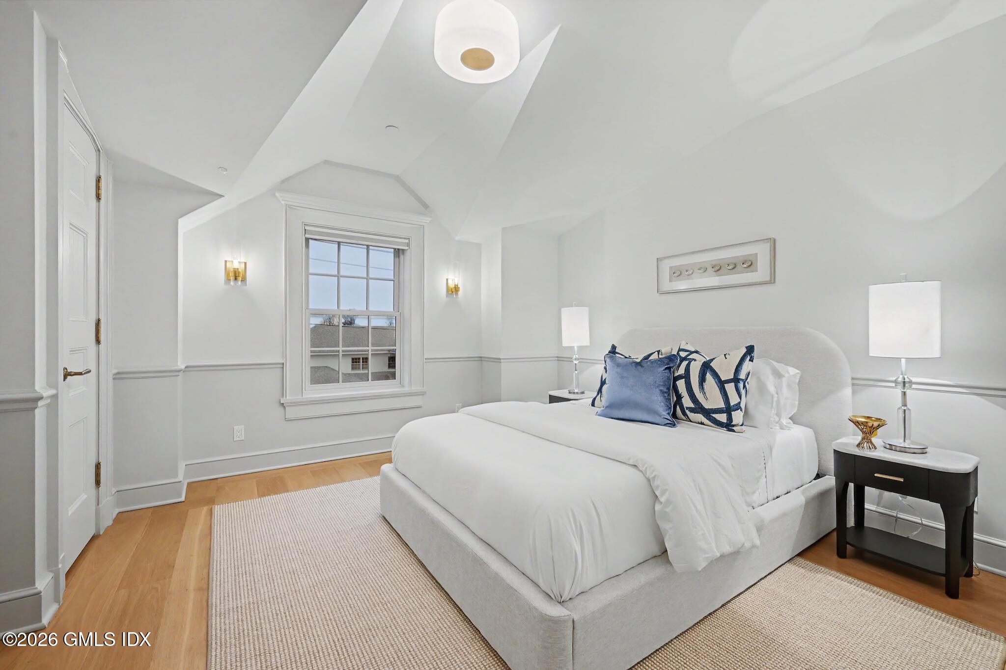 702 Steamboat Road, Unit 6 Greenwich, CT 06830 - Photo 24 of 45 a bedroom with a large bed and a chandelier