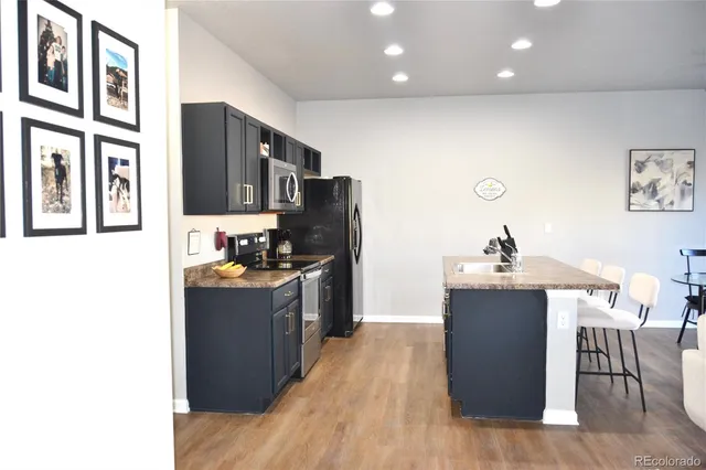 a kitchen with kitchen island stainless steel appliances a sink cabinets and wooden floor